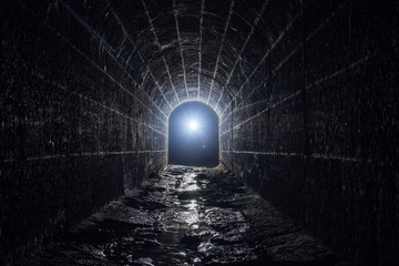 Old vaulted flooded round underground drainage sewer tunnel with dirty sewage water