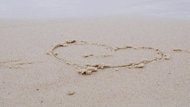 Love concept. A heart on the sea sand and waves. Spring at Baltic sea
