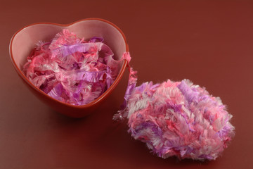 Ball of pink multicolor ribbon yarn and red and pink heart container