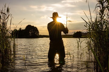 angler catching the fish during sunset