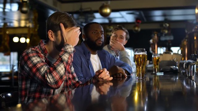 Men watching sports match in pub, upset about losing of national team, facepalm