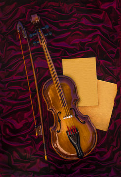 Violin, fiddlestick and two sheets on red cloth
