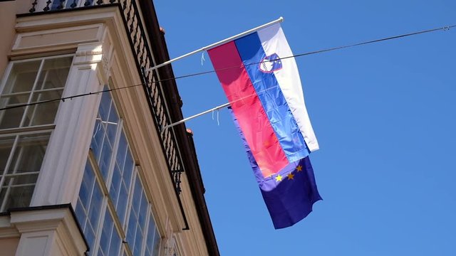 Slovakian and EU flag waving next to each other in the wind on a sunny day in Bratislava.
