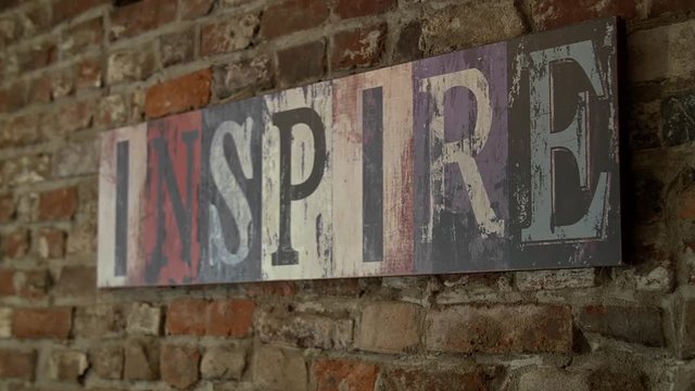 Jib up on sign that reads "inspire" hanging on brick wall