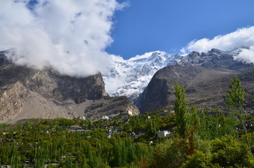 パキスタンのフンザの絶景　カリマバード中心部から見た街並みと森林　名峰ウルタルと古城のバルティットフォート