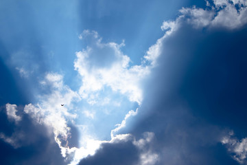 Obraz premium Blue sky with white clouds and gray cloud blue sky on a bright day with white clouds coming in floating come to cover sun causes a white beam causing beauty in the sky.