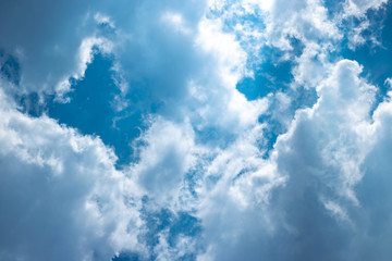 Blue sky with white clouds and gray cloud blue sky on a bright day with white clouds coming in floating come to cover sun causes a white beam causing beauty in the sky.