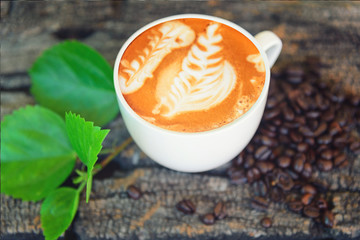hot cappuccino on wood table /hot cappuccino with coffee bean and green leaf on wood table