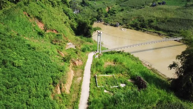 Drone shot of a road and bridge over a river on the Ma Pi Leng Pass, cyclist on the Northern Loop in Vietnam.