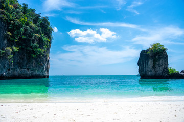 A clean white-yellow sand beach and emerald water on the island at the sea of Thailand on some holiday weekend.