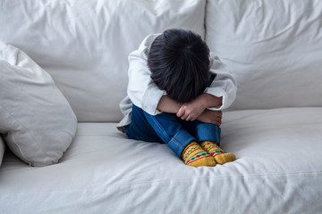 ソファの上でうずくまる男の子