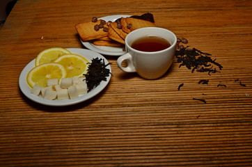 A cup of tea candy lemon cookies on a plate near the tea dumped white black green copy space