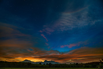 Dark starry sunset sky with mountains on horizon. Twilight sky with many stars on the sky.
