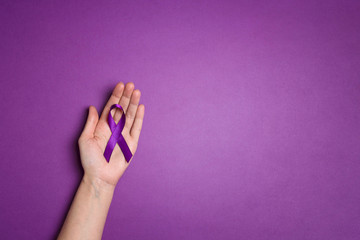 Hand holding Purple ribbons on a p urple background. World epilepsy day.
