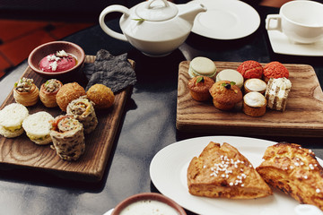 High Tea brunch spread with pastries, muffins, scones and sandwiches on a table with hot tea in Singapore