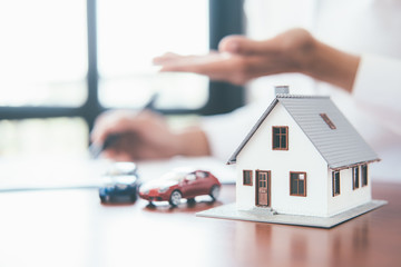 House model with real estate agent and customer discussing for contract to buy house, insurance or...