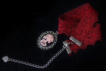 Red lace choker with skeleton girl cameo on a dark background close up