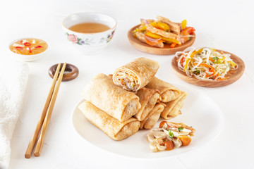 Traditional Chinese tortillas filled - bings in a plate on a white background, salads, Dam Sam snacks and cup of tea.
