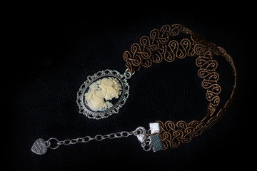 Brown necklace with girl cameo on a dark background close up