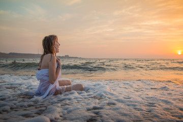 Fototapeta na wymiar Girl rests and has fun in sea wave at sunset