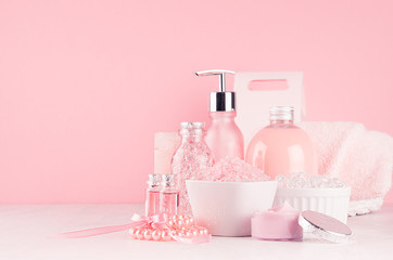 Obraz na płótnie Canvas Elegant pink skin and body care products - cream, rose oil, liquid soap, salt, cotton towel and box - cosmetic accessories on white wood table, copy space.