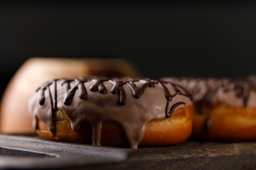 Cookery, baking and food concept - closeup. Two donuts in the glaze on the decorative board.