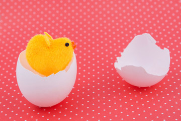Yellow toy chicken hatched egg shell on a red background. Easter background. Horizontal