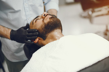 A man in a barbershop. Clipping beard in the barber. Rest in hairdressing salon