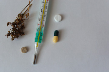 To the left of the thermometer, natural herbs treatment to the right with pills