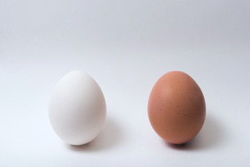 Two eggs on a white background, white and brown. Minimalism.