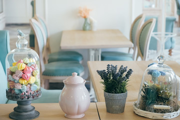 A table with decorations on it, colors, sweets and sugar bowl. Blurred chairs, a table, a light cafe room.