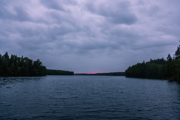 The last rays of the sun late in the evening over a small forest lake in Karelia. Russia