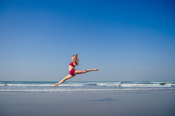 Gymnast girl doing splits grand jete in the air. Beautiful young fit gymnast woman working out,...