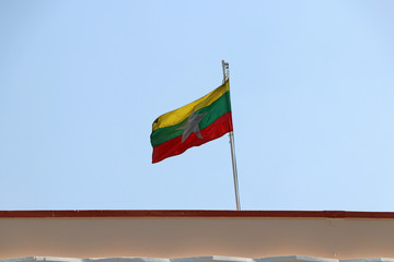 Myanmar flag blown by the wind on the roof with blue sky background.