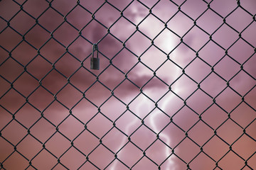 Fototapeta premium Conceptual image of lightning in the stormy sky and steel mesh wire fence. Concept of hope and freedom