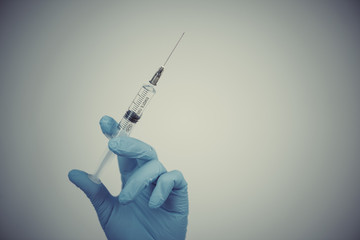 Woman in medical rubber gloves with a syringe in her hand