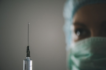 Woman in medical mask with a syringe in her hand