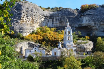 View of one of the temples in the Bakhchisaray Cave Monastery, also known as Assumption Monastery of the Caves, in mid-autumn. Many trees around have already turned yellow.