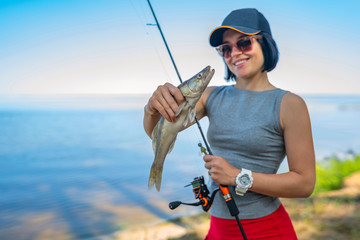 Happy fisher girl with walleye zander fish trophy at lake shore