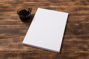 Blank paper notebook on brown wooden table background. Top view with copy space
