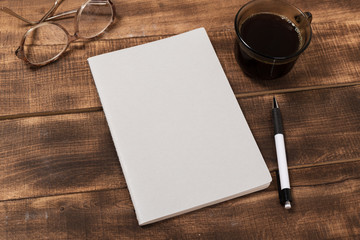 top view image of open notebook with blank pages next to cup of coffee on wooden table. ready for adding text or mockup.