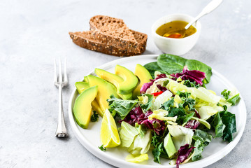 salad  of avocado, egg, green kale and spinach. olive oil in a white cup. on a white plate, grain bread, diet food, organic vegetables.  food flat lay, salad recipe,  light background