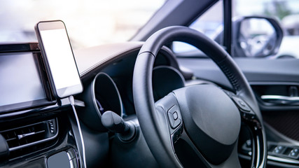 Smartphone with white blank screen mounting with magnet on the car console near steering wheel....