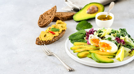 food for a healthy Breakfast or lunch. salad of avocado, kale leaves, egg and spinach, on a white plate, grain bread, diet food, organic vegetables, food flat lay