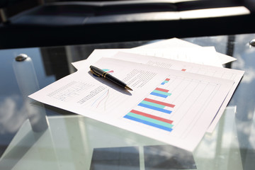 financial chart and pen on glass table in office