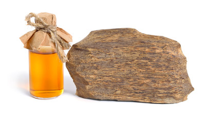 Agarwood, also called aloeswood oudh. With essential oil in pharmaceutical bottle. Isolated on white background