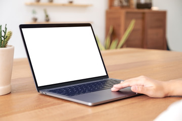 Mockup image of hands using and touching on laptop touchpad with blank white desktop screen on wooden table