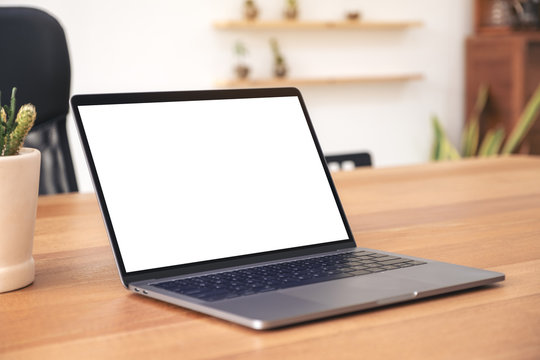 Mockup image of laptop with blank white desktop screen on wooden table