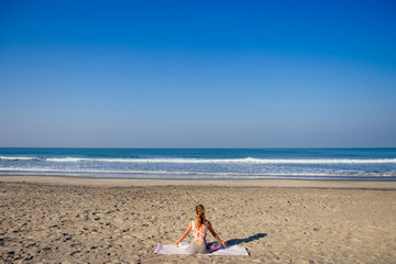 Fototapeta na wymiar Caucasian woman practicing yoga at seashore morning summer beach