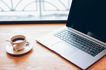 Open laptop and a Cup of coffee on the table in the cafe, freelance concept